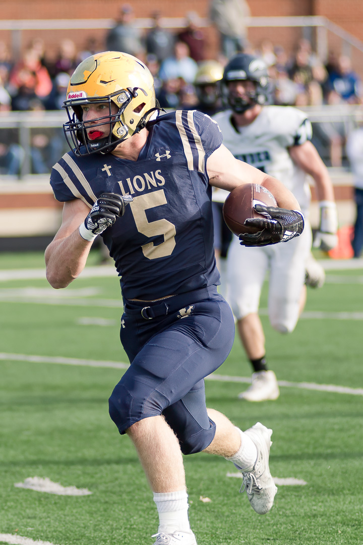 High school football player running with the ball.