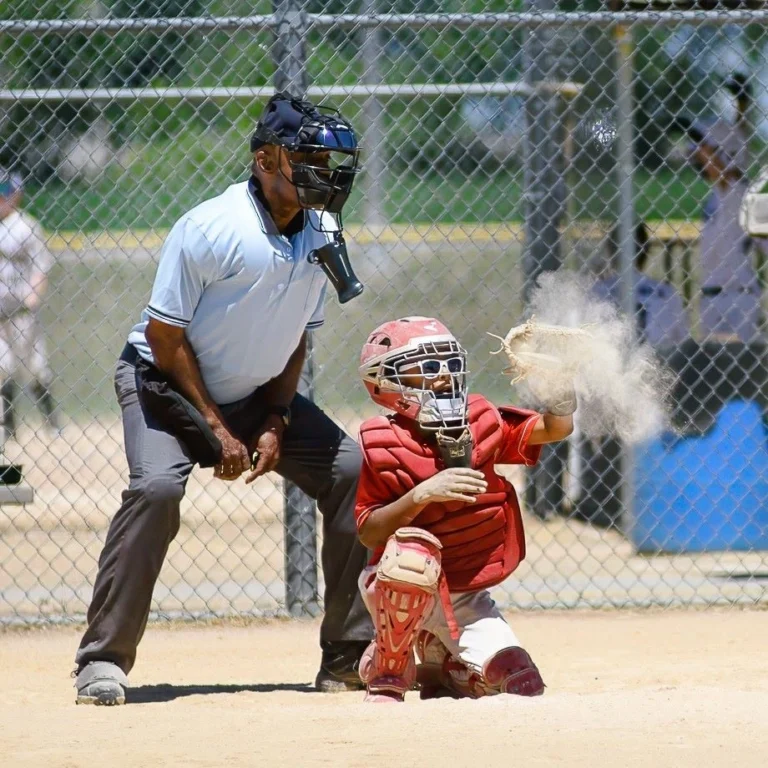 Youth baseball catcher snags a pitch in a cloud of chalk dust during a Minnesota game day