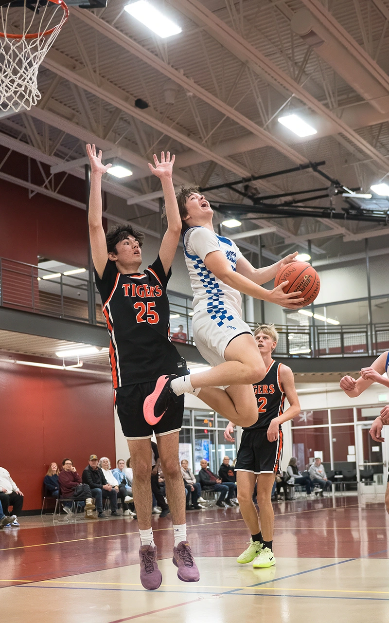 High school basketball player drives past Tigers defender for a layup during a Minnesota game day