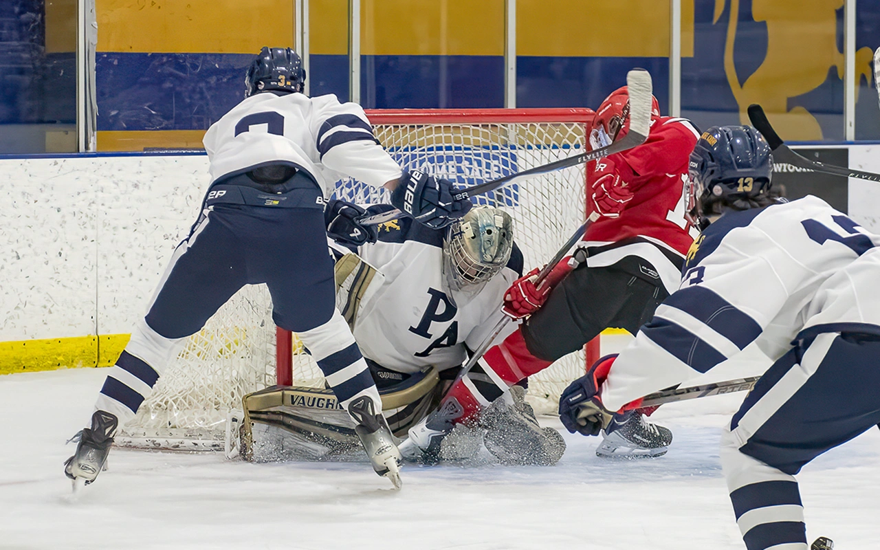 High school hockey goalie makes a desperation save in a goal mouth scramble during a Minnesota game