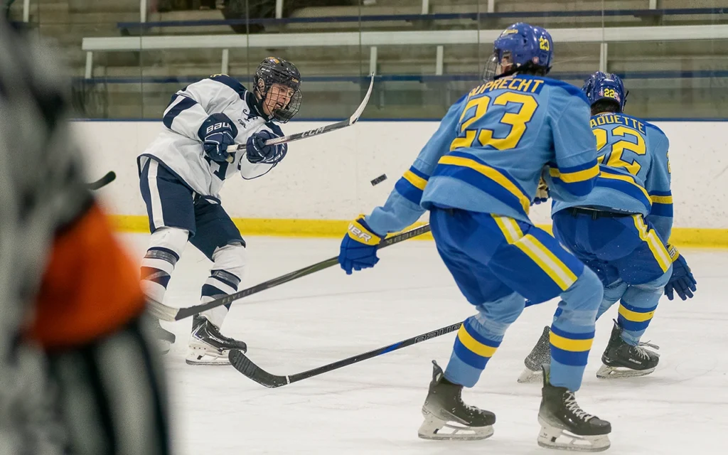 High school hockey player fires a shot on goal through two defenders during a Minnesota game day