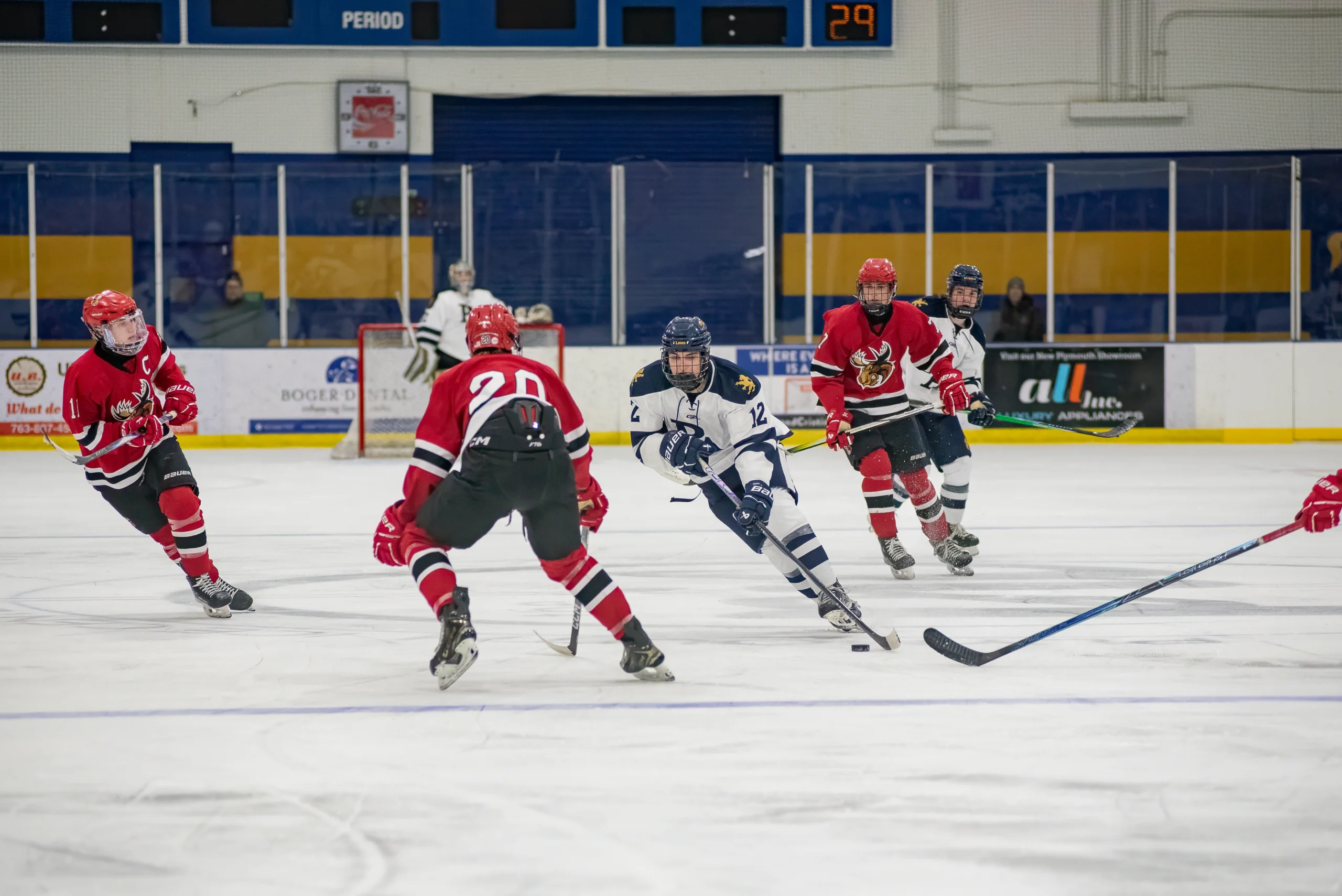 Youth hockey player drives the puck across the blue line during a Minnesota high school hockey game