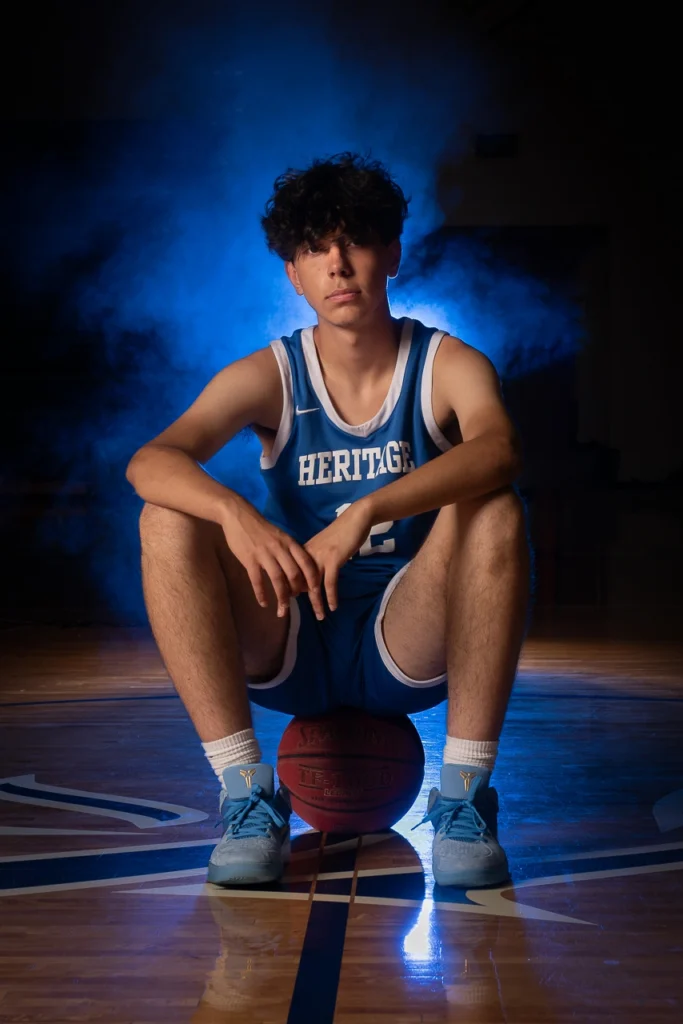 Heritage basketball player sits on ball with dramatic blue smoke lighting — Sportraits athlete portrait add-on Twin Cities