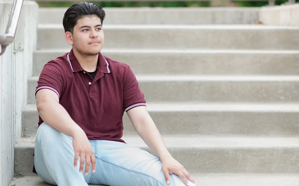 Relaxed high school senior guy sits on outdoor steps looking off camera — Twin Cities senior portrait photography