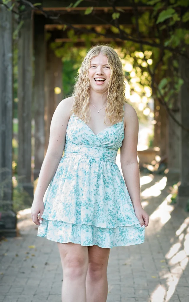 igh school senior girl laughs walking under garden arbor in floral sundress — Plymouth Minnesota senior photographer