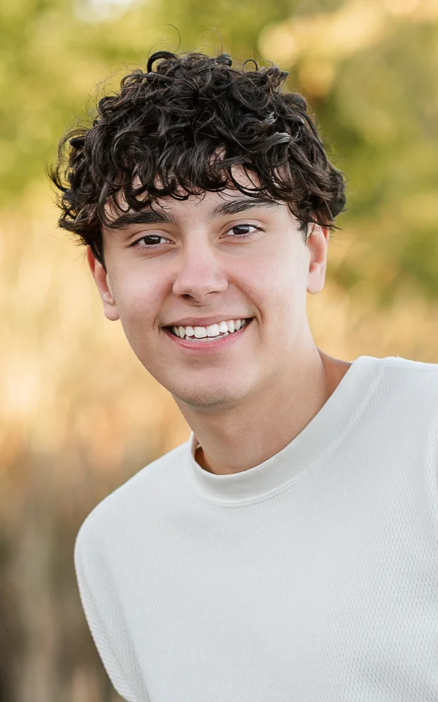 Close-up senior portrait of smiling high school guy with curly hair in autumn light — Plymouth Minnesota senior photographer