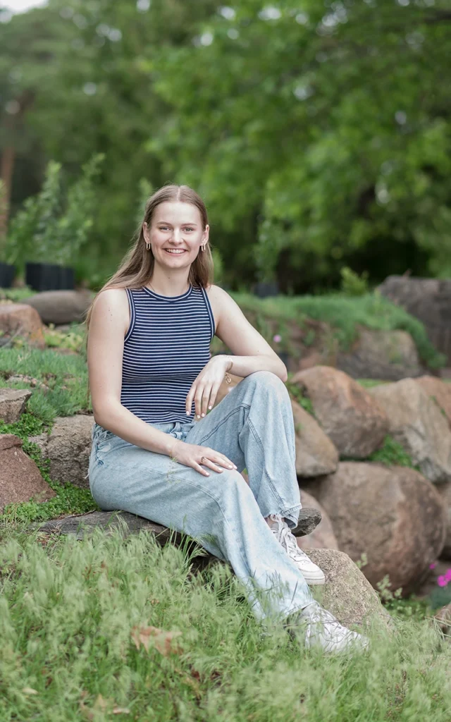 igh school senior girl sits on rocks smiling in striped tank and jeans — Minnetonka Minnesota senior portrait photographer