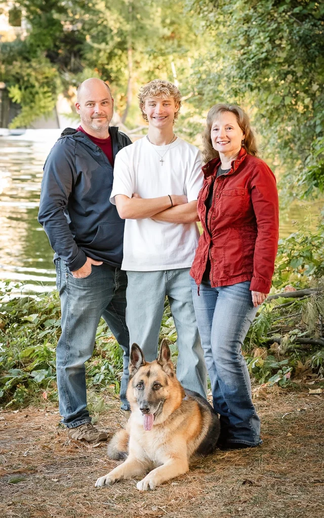 High school senior portrait with parents and German Shepherd dog outdoors by the water — Twin Cities family add-on session
