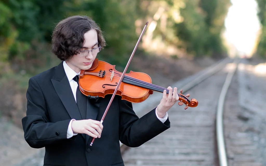 High school senior guy plays violin in formal suit on railroad tracks — New Hope Minnesota senior portrait photographer