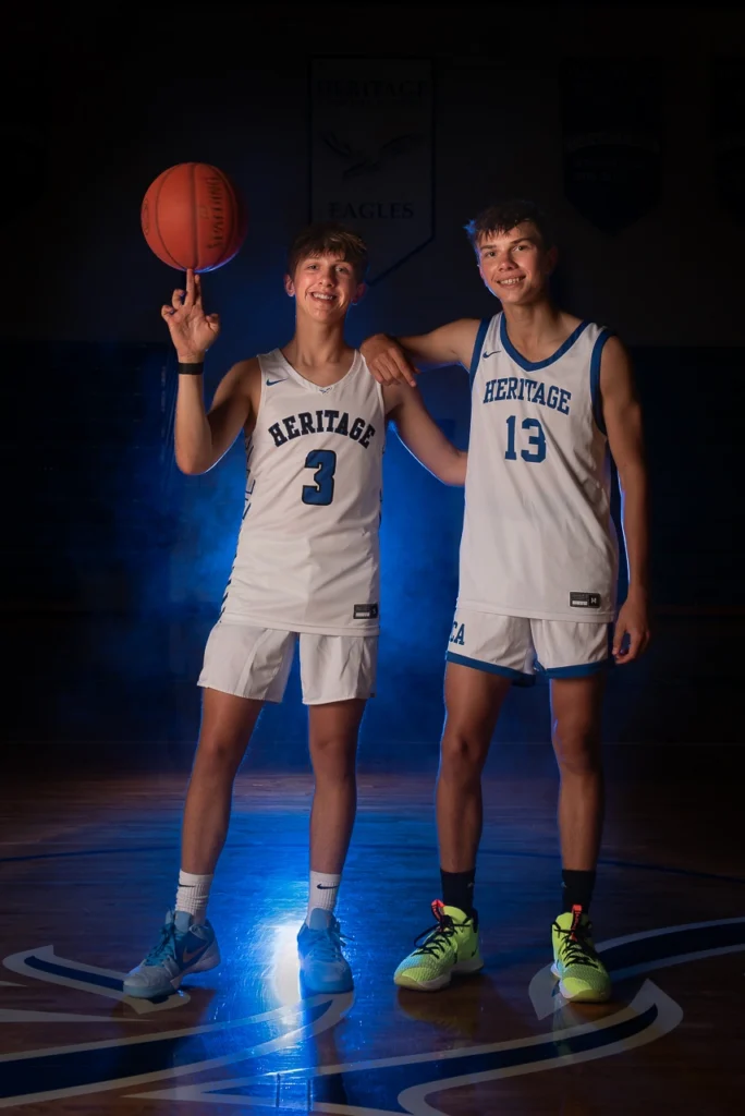 Sports portrait of two Heritage Eagles basketball players with blue smoke lighting on home court — Twin Cities athlete photography