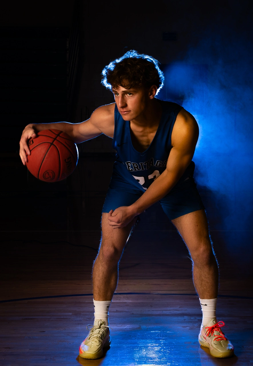 Dramatic sports portrait of Heritage high school basketball player dribbling with blue smoke lighting — Twin Cities athlete photography