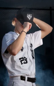 Dramatic sports portrait of Twin Cities travel baseball player tipping hat with blue smoke background