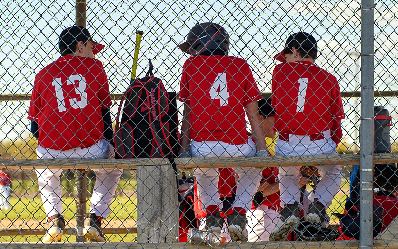 Travel baseball players watch from the dugout during a Minnesota tournament game day