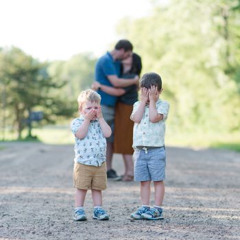 parents kissing with kids covering eyes in foreground